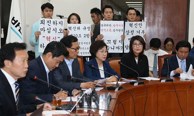 손학규(왼쪽) 바른미래당 대표가 22일 오전 국회에서 열린 최고위원회의에서 당 혁신위원들이 혁신안 수용을 촉구하며 자신을 비판하는 내용의 팻말을 들고 선 가운데 모두발언을 하고 있다.