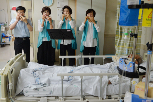 대경상록 하모니카 동아리 봉사단이 7월 22일 대구 동구 신암동 대구파티마병원 5층 호스피스 완화의료센터 병실 한 환자 앞에서 평안을 기원하며 하모니카 연주를 하고 있다.  김낙중 기자