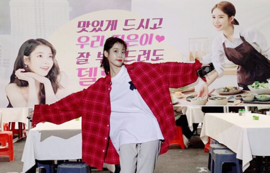 아이유가 유인나가 보낸 밥차 플래카드 앞에서 두 팔 벌려 고마움을 표시하고 있다.