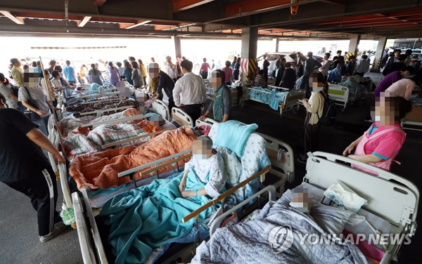 (김포=연합뉴스) 24일 오후 경기도 김포시 풍무동 김포요양병원 화재 현장에서 대피한 환자들이 인근 주차장에서 병원 호송 차량을 기다리고 있다.