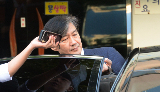조국 법무부 장관이 4일 오전 아내 정경심 동양대 교수의 검찰 소환 조사에 대한 심경을 묻는 기자들의 질문을 피하면서 출근을 위해 서울 서초구 방배동 자택 앞에 대기 중인 차량에 탑승하고 있다.
