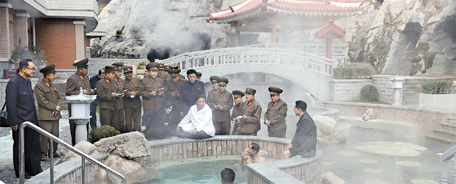 김정은(가운데) 북한 국무위원장이 완공을 앞둔 평안남도 양덕군 온천관광지구 건설장을 50여 일 만에 방문, 야외 온천장 가장자리에 앉아 관계자들에게 ‘우리식 건축’을 강조하는 모습을 담은 사진을 조선중앙통신이 25일 공개했다. 연합뉴스