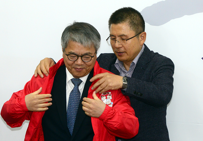 황교안(오른쪽) 자유한국당 대표가 31일 오전 국회에서 열린 1차 영입 인재 환영식에서 국민연금 전문가로 영입된 김용하 전 보건사회연구원장에게 한국당 점퍼를 입혀주고 있다.  김선규 기자