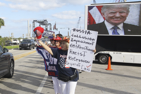 도널드 트럼프 미국 대통령의 지지자들이 1일 플로리다주의 한 도로에서 플래카드를 들고 응원을 펼치고 있다. 이들은 트럼프 대통령을 태운 자동차 행렬을 보기 위해 거리로 나섰다. AP 연합뉴스