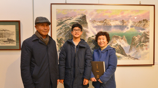 인천문화예술회관 전시장을 찾은 고 황영준 화백의 막내딸 황명숙(오른쪽) 씨와 남편 박완규(왼쪽) 씨, 그리고 이 두 사람의 외손자인 이다함 군.  경인일보 제공