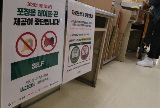 지난 19일 서울 성동구의 한 대형마트 자율포장대에 고객들이 구매한 물품을 담아가도록 포장용 박스가 비치된 가운데 ‘포장용 테이프·끈 제공 중단’을 알리는 안내문이 게시돼 있다. 서종민 기자