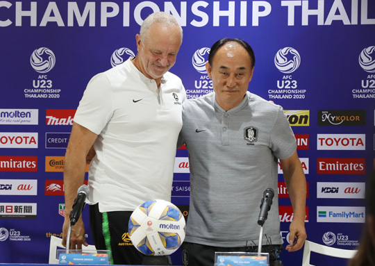 김학범(오른쪽) 대표팀 감독과 그레이엄 아널드 호주 감독이 21일 태국 방콕의 라자망갈라 스타디움에서 공식 기자회견을 마친 뒤 어깨동무를 하고 있다.   연합뉴스