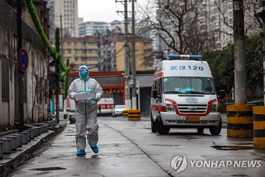 (우한 EPA=연합뉴스) ‘우한 폐렴’(신종 코로나바이러스 감염증) 발원지인 중국 후베이성 우한의 한 거리에서 지난 26일 보호복을 착용한 구급요원이 의료용품 상자를 들고 병원으로 향하고 있다.