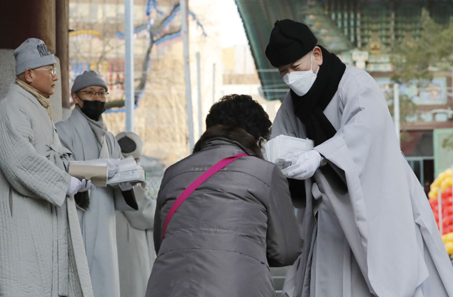 마스크를 착용한 지현 조계사 주지 스님이 4일 오전 서울 종로구 조계사 일주문 앞에서 신종 코로나바이러스 감염증(우한 폐렴) 예방을 위해 신도들에게 마스크를 나누어 주고 있다. 뉴시스
