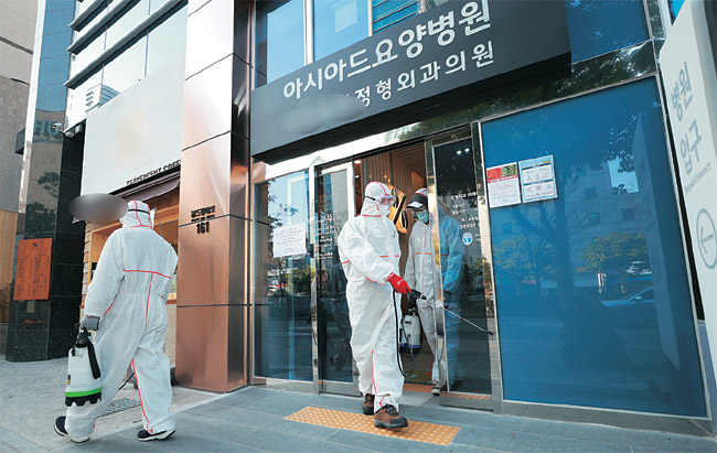 병원 사회복지사가 신종 코로나바이러스 감염증(코로나19) 확진 판정을 받아 코호트 격리(동일집단 전원 격리) 조치가 취해진 부산 연제구 아시아드요양병원에서 24일 오전 병원 관계자가 방역을 하고 있다.  연합뉴스