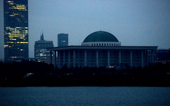 신종 코로나바이러스 감염증(코로나19) 확산 여파로 헌정사상 처음으로 국회가 폐쇄된 25일 오전 서울 강변북로에서 바라본 여의도의 모습. 민간 기업들이 입주한 빌딩들이 불을 밝히고 있는 것과 대조적으로 국회 본관은 모든 조명이 꺼져 있다.