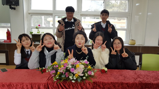 김정미(가운데) 교사가 경북 포항 남구 대보중 재직 당시 담임을 맡은 반 학생들과 졸업식 후 기념사진 촬영을 하고 있다. 김정미 교사·초록우산어린이재단 제공