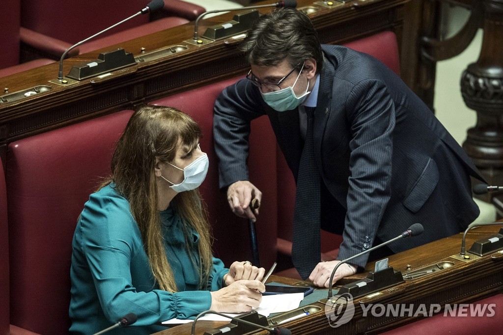 이탈리아에서 신종 코로나바이러스 감염증(코로나19)이 확산되고 있는 가운데 하원 의사당에서 25일(현지시간) 마테오 달로소 의원(오른쪽)과 테레사 발디니 의원이 마스크를 쓰고 대화를 나누고 있다.