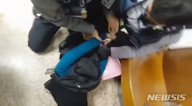 [서울=뉴시스]지난달 서울 잠실역에서 경찰 두명이 한 여성의 등 뒤로 수갑을 채우고 있다. 2020.03.04. (사진=유튜브 캡처)