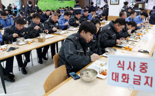 인천 연수구 해양경찰청 경찰관들이 5일 코로나19 감염을 방지하기 위해 ‘식사 중 대화 금지’라고 적힌 안내 문구가 있는 테이블에서 마주 보지 않고 일렬로 앉아 점심 식사를 하고 있다.  뉴시스