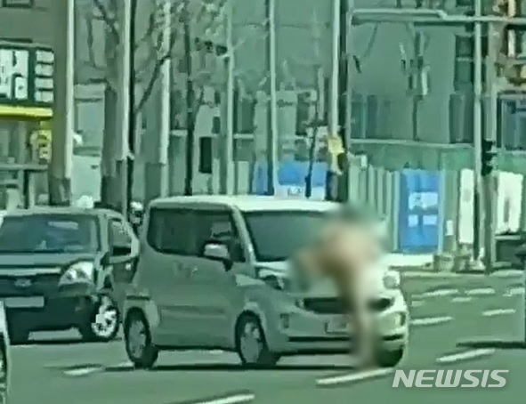 [울산=뉴시스] 지난 22일 오전 11시30분께 남구 삼산동 농수산물도매시장 앞 도로에서 30대 A씨가 나체로 차량에 올라타 폭력을 행사하고 있다.(사진=독자 제공)