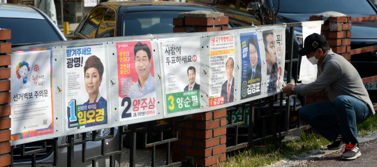 21대 국회의원 총선거 공식 선거운동이 시작된 2일 오전 경기 광명시 철산사거리 인근에서 지역 선거관리위원회 관계자가 광명갑 선거구 후보자들을 소개하는 선거 벽보를 붙이고 있다.   곽성호 기자