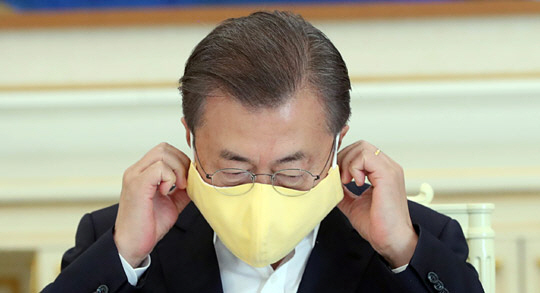 문재인 대통령이 지난 3월 18일 청와대에서 신종 코로나바이러스 감염증(코로나19) 대응 방안을 논의하기 위해 개최한 경제주체 초청 원탁회의에서 발언에 앞서 착용한 마스크를 벗고 있다. 연합뉴스