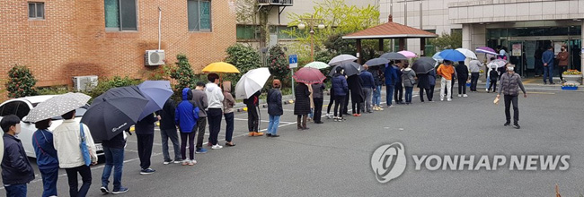 11일 오후 울산시 남구 옥동 울산보훈지청 사전투표소에서 줄을 길게 늘어선 유권자들이 갑작스럽게 비가 내리자 우산을 꺼내 쓰거나 그대로 비를 맞으면서 투표 순서를 기다리고 있다. [연합뉴스 자료사진]