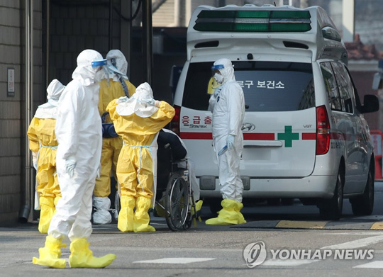 (서울=연합뉴스) 2020년 2월 20일 서울 중구 국립중앙의료원에 종로구 보건소 구급차를 타고 온 신종 코로나바이러스 감염증(코로나19) 유증상자가 의료진과 함께 휠체어를 탄 채 이동하고 있다. [연합뉴스 자료사진]