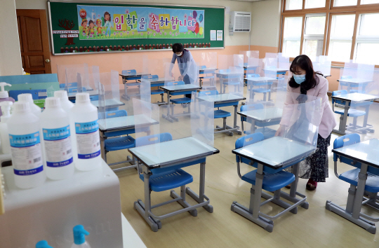 초등학교 등교 개학을 이틀 앞둔 25일 인천 부평구의 한 초등학교에서 선생님들이 칸막이가 설치된 책상의 배치를 살피고 있다. 뉴시스