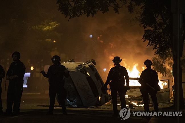 (워싱턴 AP=연합뉴스) 미국 수도 워싱턴DC 백악관 인근에서 지난달 31일(현지시간) 백인 경찰의 가혹 행위로 흑인 남성 조지 플로이드가 사망한 사건에 대한 항의 시위가 벌어진 가운데 경찰이 화재 발생 현장 주변에 서 있다.