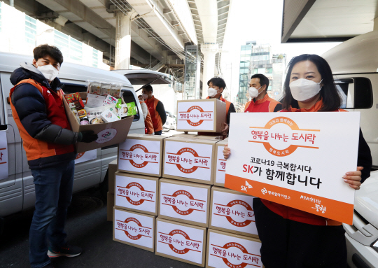SK그룹 구성원들이 지난 1월 서울 성북구 정릉로 행복도시락 북부플러스센터에서 행복도시락과 행복상자를 포장하고 기념 촬영을 하고 있다. SK그룹은 신종 코로나바이러스 감염증으로 어려움을 겪은 대구·경북지역 어린이 1500명에게 행복도시락과 행복상자를 전달했다.   SK그룹 제공