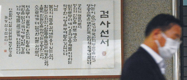 당·정·청의 검경수사권 조정 확정과 법무부의 총장 수사지휘권 폐지, 검찰 내부의 대립·갈등으로 조직 분위기가 뒤숭숭한 검찰에서 30일 오전 서울중앙지검의 한 직원이 검사선서가 담긴 액자 앞을 지나 출근하고 있다.  신창섭 기자