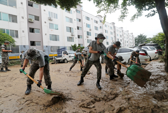 31일 오전 대전 서구 정림동 코스모스아파트에서 군 장병들이 집중호우에 떠내려온 토사를 치우고 있다. 전날 내린 20년 만의 기록적인 폭우에 이 아파트 1층의 28가구가 침수되는 등 피해가 속출했다.  연합뉴스