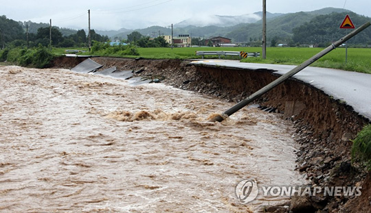 (충주=연합뉴스)  2일 오전 집중호우로 충북 충주시 산척면 도로가 유실되면서 전신주가 쓰러져 있다. 2020.8.2