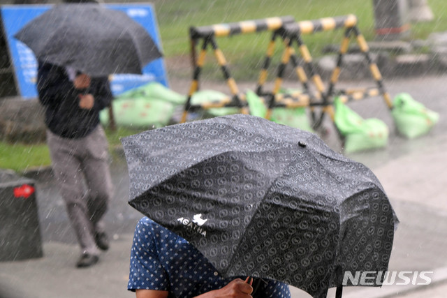 [부산=뉴시스] 하경민 기자 = 지난 10일 오후 해운대해수욕장을 찾은 시민들이 비바람에 맞서 힙겹게 걸어가고 있다. 2020.08.10.