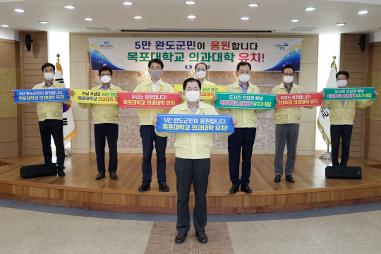 신우철(가운데) 완도군수가 지난 11일 전남 서남권 의대 유치를 위한 서명 운동 및 홍보를 위해 ‘목포대 의과대학’ 유치를 기원하는 릴레이 캠페인에 동참했다.  완도군청 제공