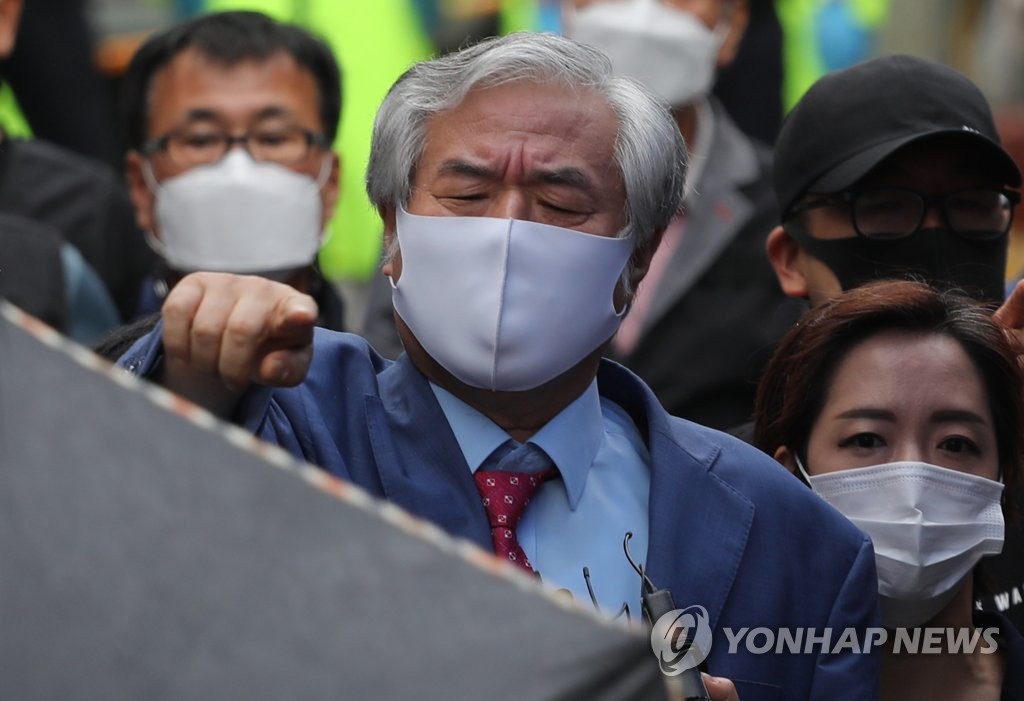 보석 취소로 재수감되는 전광훈 목사가 지난 7일 오후 성북구 사랑제일교회 앞에서 기자회견 전 자신을 가리던 파라솔과 우산을 치우라는 손짓하고 있다.
