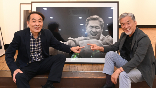 김녕만(왼쪽) 사진작가와 소리꾼 장사익이 지난 6일 서울 인사동 경인미술관 전시장의 사진 앞에서 익살스럽게 우정 포즈를 취하며 함께 웃고 있다.