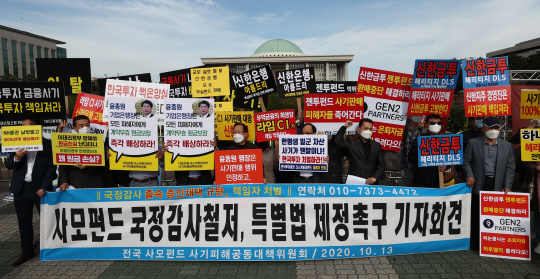 ‘옵티머스·라임자산운용 펀드 사기 사건’의 정·관계 연루 의혹이 확산하는 가운데 전국 사모펀드 사기피해공동대책위원회 관계자들이 13일 오전 국회 정문 앞에서 사모펀드에 대한 철저한 국정감사와 특별법 제정을 촉구하는 기자회견을 열고 구호를 외치고 있다.  연합뉴스