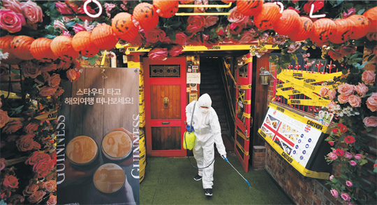 핼러윈데이를 이틀 앞둔 29일 서울 용산구 이태원 거리에서 주민자치위원회 관계자가 신종 코로나바이러스 감염증(코로나19) 확산 방지를 위해 방역 작업을 하고 있다.   연합뉴스