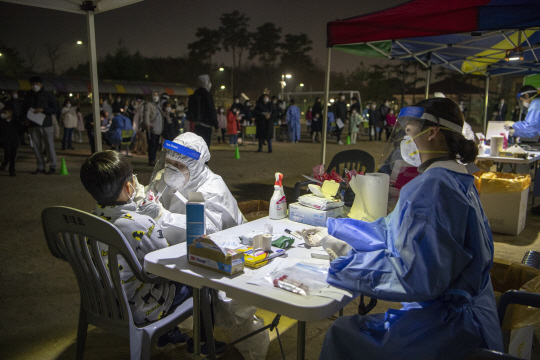 코로나19 확진 판정을 받은 원주시 일가족 4명의 접촉자인 어린이가 16일 저녁 강원 원주시 반곡동 봉대초에 설치된 선별진료소에서 야간에 긴급 진단검사를 받고 있다. 원주시 제공