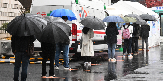 코로나19 확진자가 343명 발생한 19일 오전 시민들이 서울 중구 국립중앙의료원 선별진료소를 찾아 우산을 쓰고 진단검사 순서를 기다리고 있다. 이날 서울 아침 최저기온은 17.1도로 역대 11월 중 가장 높았으며 일강수량도 11월 기준으로 기상 관측 이래 가장 많은 68.2㎜를 기록해 이상기후를 나타냈다.  김호웅 기자