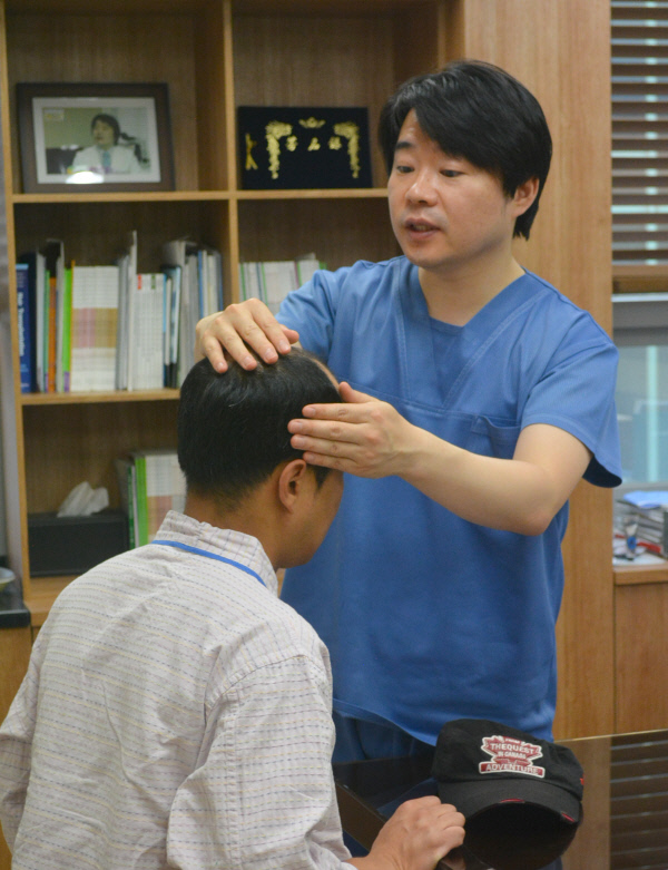 나용필 나용필모피부과의원 원장이 남성형 탈모환자의 두피 상태를 점검하고 있다.