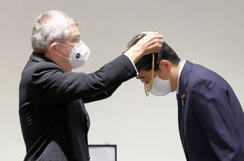 토마스 바흐 국제올림픽위원회(IOC) 위원장이 지난 16일 도쿄 올림픽박물관에서 아베 신조 전 일본 총리에게 ‘올림픽 훈장’을 걸어 주고 있다. [교도=연합뉴스 자료사진]