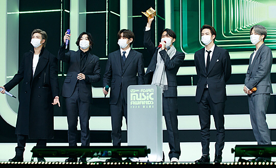6일 온라인으로 중계된 ‘2020 엠넷 아시안 뮤직 어워즈’에서 대상을 받은 그룹 방탄소년단이 마스크를 착용하고 트로피를 높이 들며 소감을 말하고 있다.  CJ ENM 제공