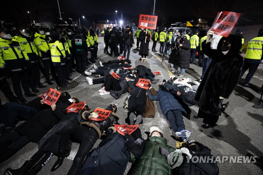 아동 성범죄자 조두순이 출소한 12일 오전 구로구 서울남부교도소 앞에서 조두순의 출소를 반대하는 집회 참가자들이 바닥에 누워 구호를 외치고 있다.