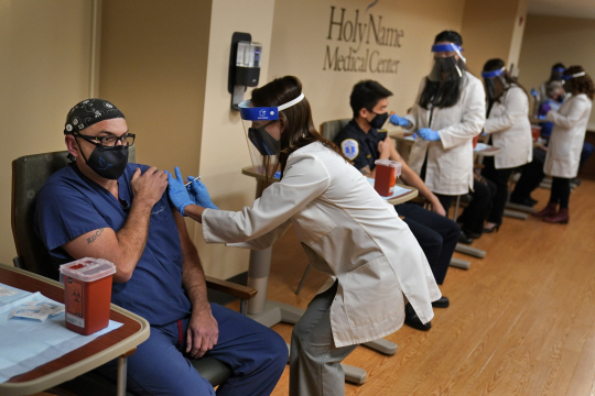 17일 미국 뉴저지 티넥의 홀리 네임 병원에서 간호사 등 필수의료인력들이 눈보라를 뚫고 도착한 신종 코로나바이러스 감염증(코로나19) 백신을 맞고 있다. 미국은 지난 14일부터 화이자 백신 접종을 개시했으며, 다음 주에는 모더나 백신 접종도 시작될 것으로 보인다.  AP 연합뉴스
