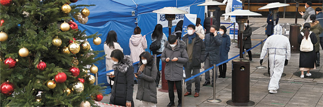 크리스마스이브인 24일 오전 서울 서초구 강남역 인근에서 시민들이 신종 코로나바이러스 감염증(코로나19) 검사를 받기 위해 임시선별진료소를 찾은 가운데 크리스마스트리가 장식돼 있다.