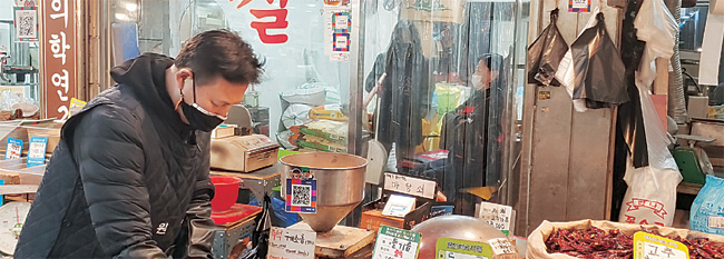 지난 23일 서울 마포구 망원시장 ‘깨가 쏟아지는 마당쇠’ 상점에서 점주 고종순 씨가 깨소금을 담고 있다. 이 가게에는 모바일 온누리상품권을 사용할 수 있도록 제로페이 QR코드가 부착돼 있다.