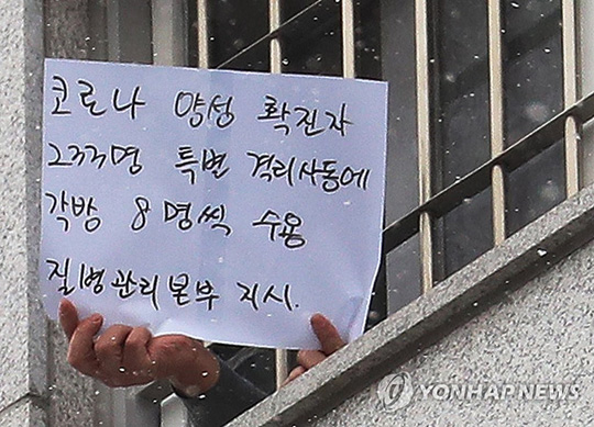 (서울=연합뉴스) 29일 오후 서울 송파구 동부구치소에서 한 수용자가 확진자 과밀수용 등 불만 사항을 직접 적어 취재진을 향해 들어 보이고 있다. 어제 동부구치소에서 233명의 확진자가 추가돼 지금까지 이곳에서만 총 757명이 감염됐다. 2020.12.29