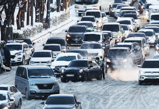 7일 오전 경기 수원시 영통구 광교로 도로가 극심한 교통정체를 빚으면서 한 탑승자가 도로로 나와 빙판에 갇혀 바퀴가 헛도는 차량을 밀고 있다. 연합뉴스