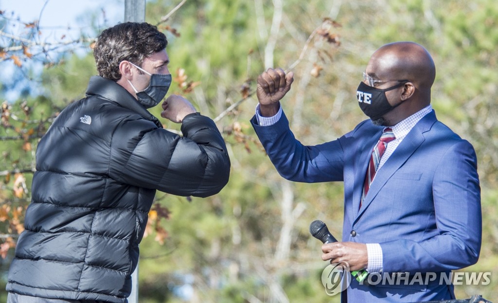 (오거스타 AP=연합뉴스) 미국 조지아주의 연방 상원의원 결선투표를 하루 앞둔 4일(현지시간) 오거스타에서 열린 민주당 측 선거 유세에서 이 당 후보 존 오소프(왼쪽)와 라파엘 워녹이 팔꿈치 인사를 하고 있다. 이들 민주당 후보는 공화당 후보인 데이비드 퍼듀, 켈리 뢰플러 현 상원의원과 경쟁하고 있다. [오거스타 크로니클 제공]