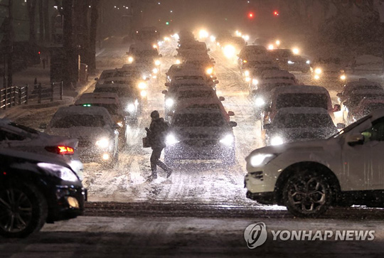 (서울=연합뉴스) 서울 전역에 대설주의보가 발효된 6일 오후 서울 삼성역 인근에서 한 시민이 횡단보도를 건너고 있다. 2021.1.6