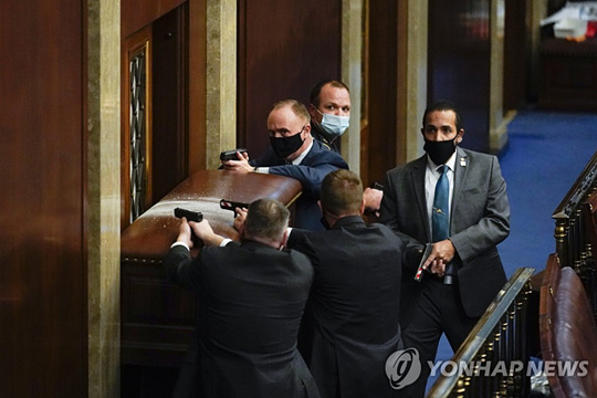 (워싱턴 AP=연합뉴스) 미국 수도 워싱턴DC 국회의사당의 하원 본회의장에서 6일(현지시간) 경찰이 시위대의 난입을 막기 위해 출입문에 집기 등으로 바리케이드를 치고 총을 겨누고 있다.